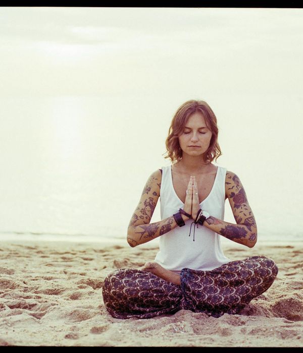 Woman sitting in a serene yoga pose outdoors at sunrise.